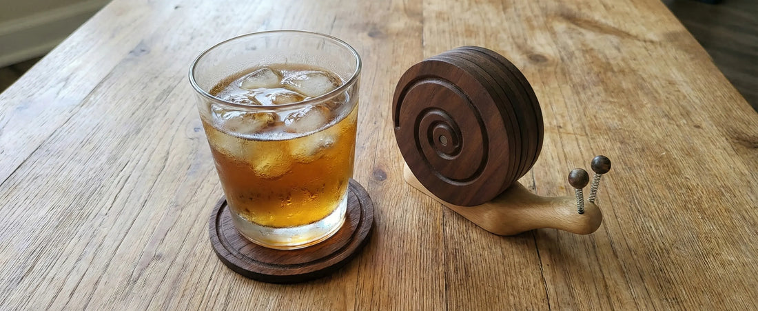 Handcrafted wooden snail coasters protecting a coffee table from condensation. Functional rustic decor that stacks into a snail shape to prevent water rings
