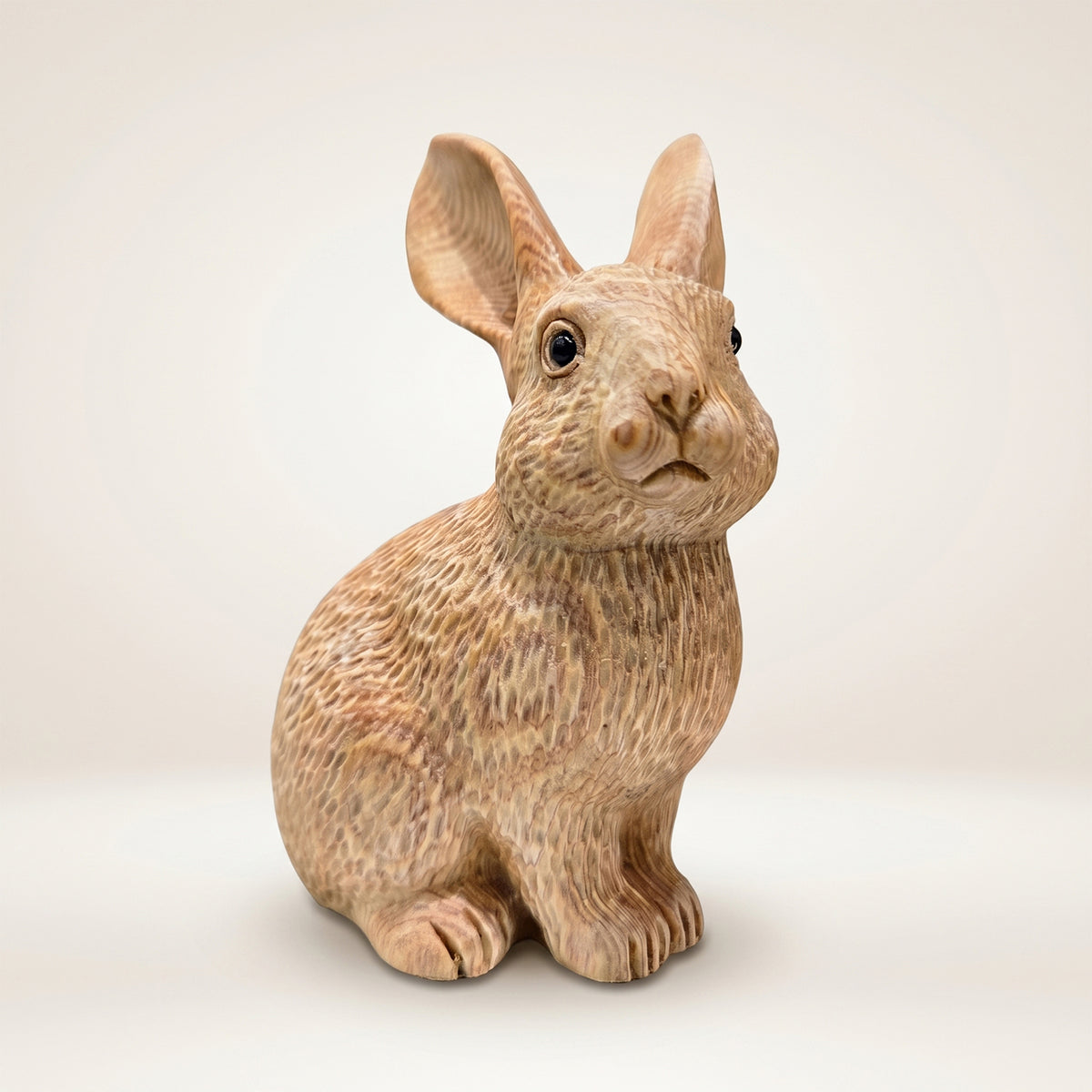 Hand-carved wooden bunny figurine sitting upright on a white background