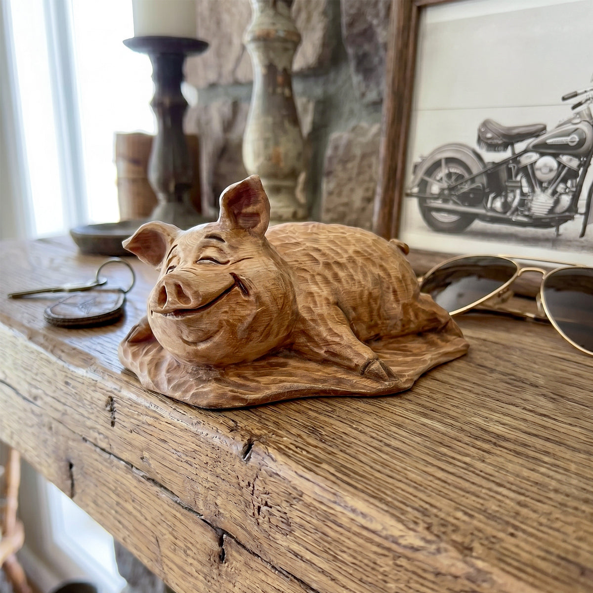 Wooden pig figurine on a wooden surface with a motorcycle print in the background
