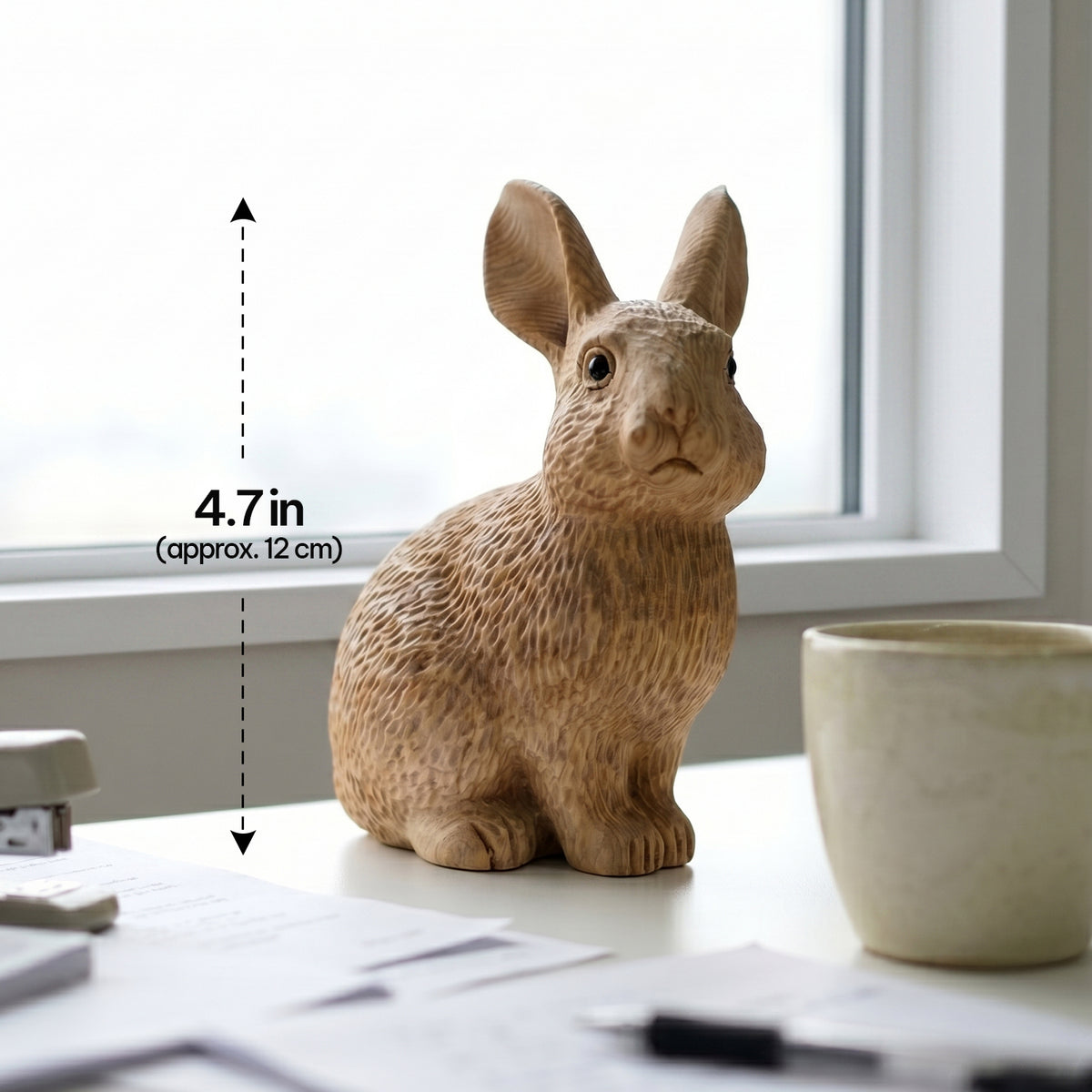 Wooden bunny figurine on a windowsill beside a mug with height labeled 4.7 inches