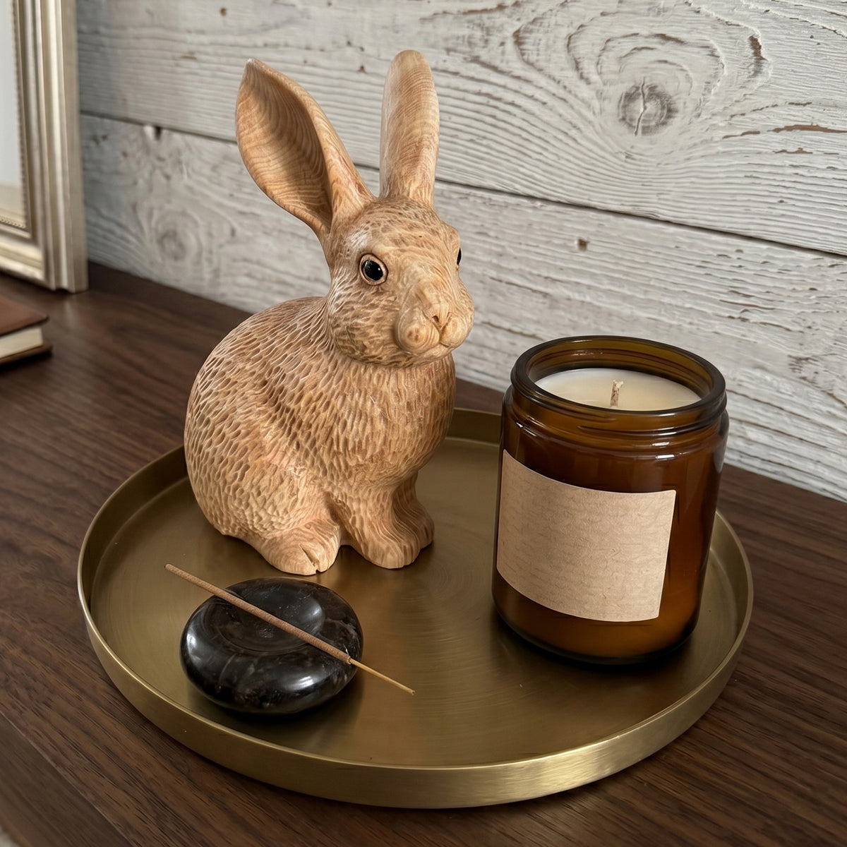 Wooden bunny figurine on a brass tray beside a candle