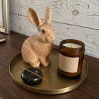 Wooden bunny figurine on a brass tray beside a candle