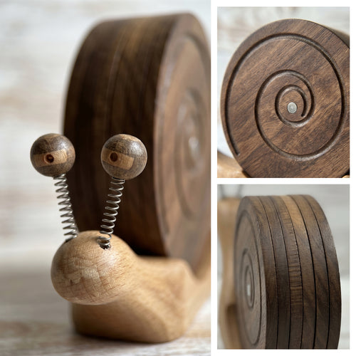 Wooden snail coaster holder with two coasters fanned out showing the spiral wood grain pattern