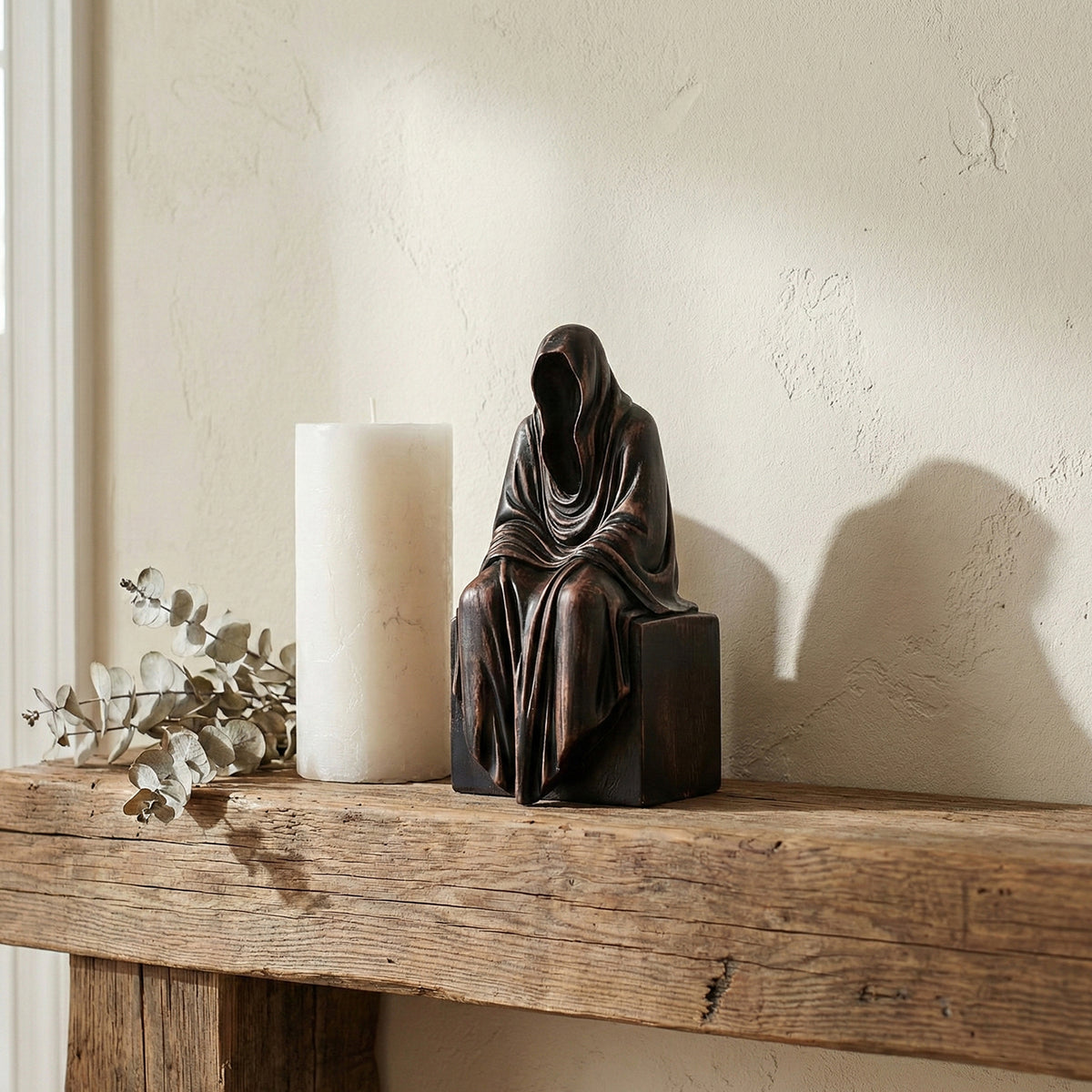 Wooden Grim Reaper figurine displayed on a mantel next to lit candles