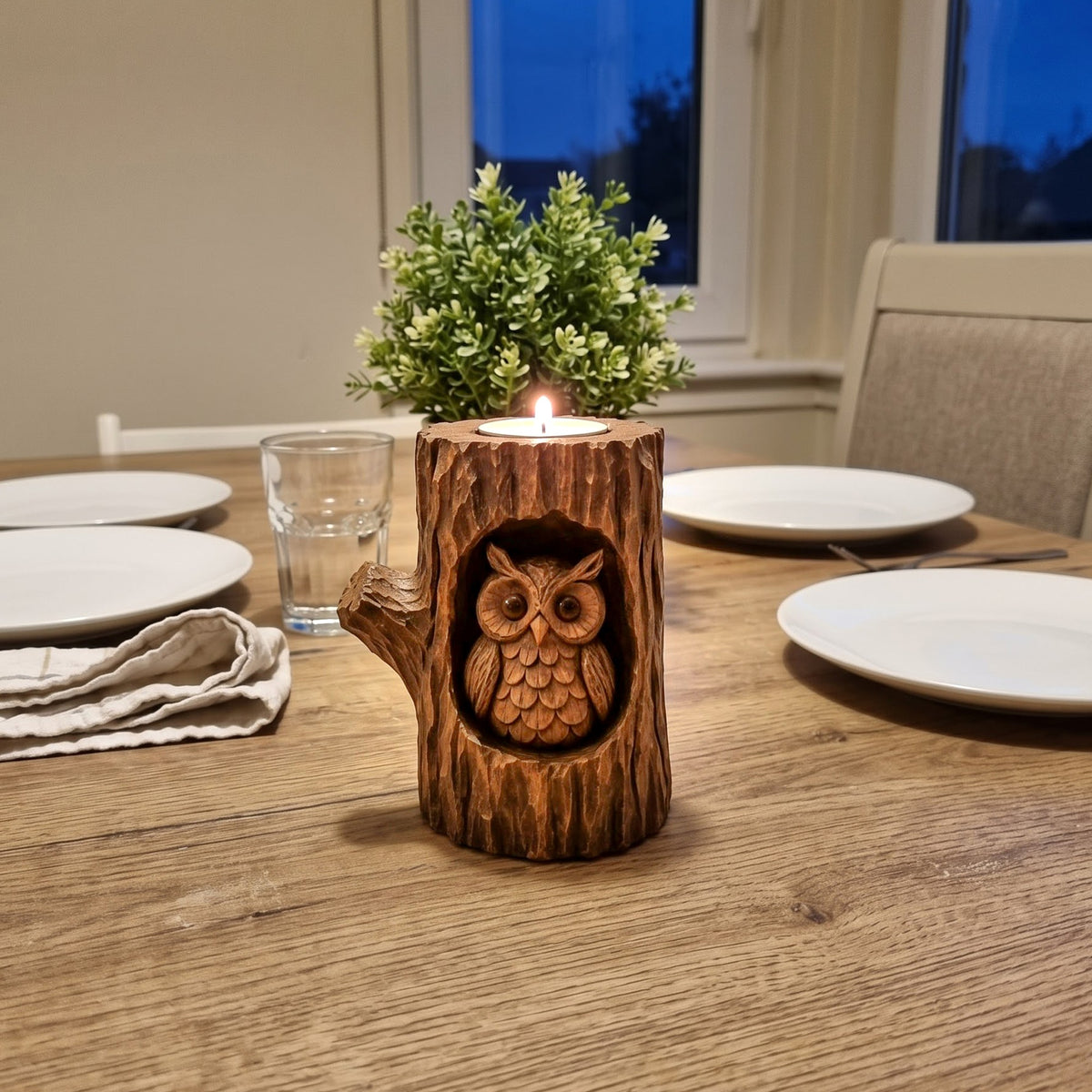 Wooden owl tealight holder used as a dining table centerpiece at dusk