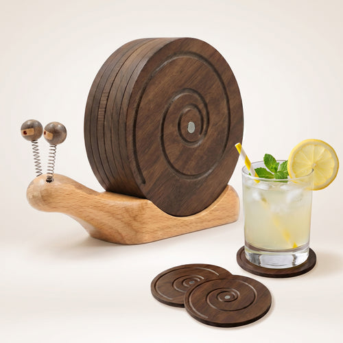 Wooden snail-shaped coaster holder with round coasters on a table beside a citrus garnished cocktail